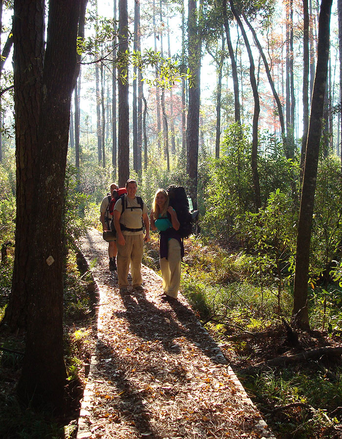 Hikers on a boardwalk trail in an Alabama forest.