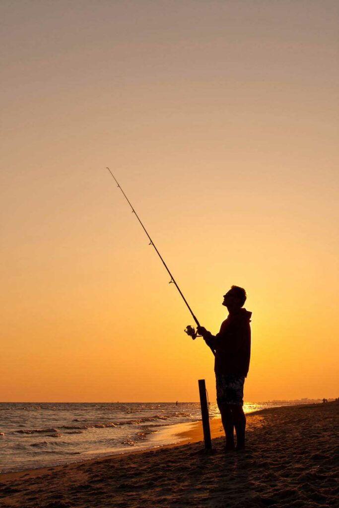 Fisher in Baldwin County, Alabama, backlit by a sunset over the water's horizion.